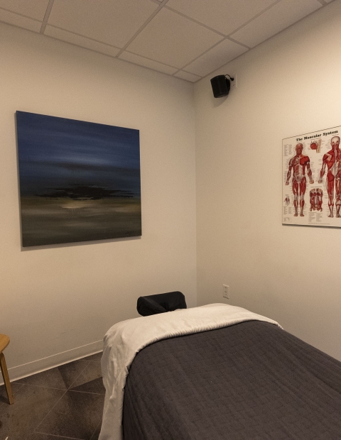 Interior of a massage room featuring a chair and a painting.