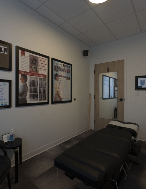 Interior of a chiropractors office with a bed and chair.