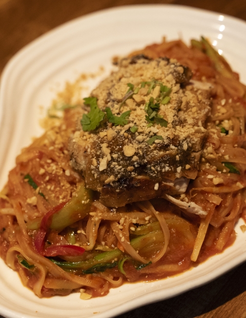 A plate of pasta with meat and vegetables, garnished with herbs and grated cheese