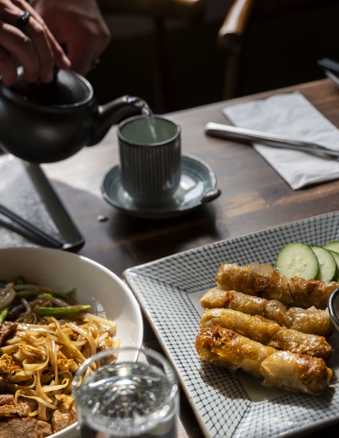 Pouring a beverage into a cup with food on the table