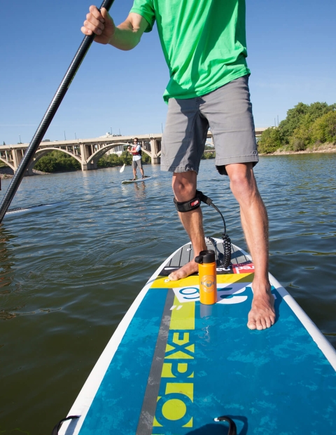 Two friends stand up paddleboarding on open water