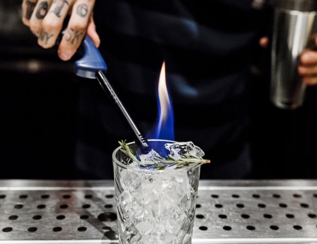 a bartender lights a cocktail on fire