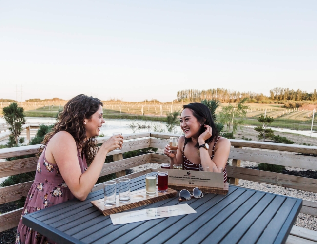 Two women sitting on a patio enjoying craft beer