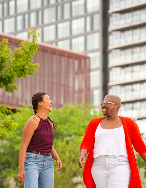 Two women talking down the city street in spring clothing