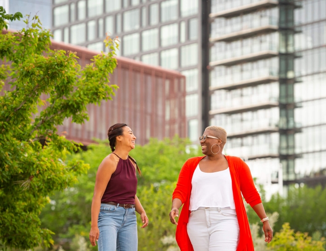 Two women talking down the city street in spring clothing