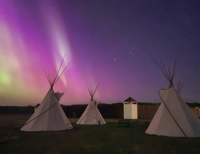 Night sky with northern lights and 3 teepees in the foreground