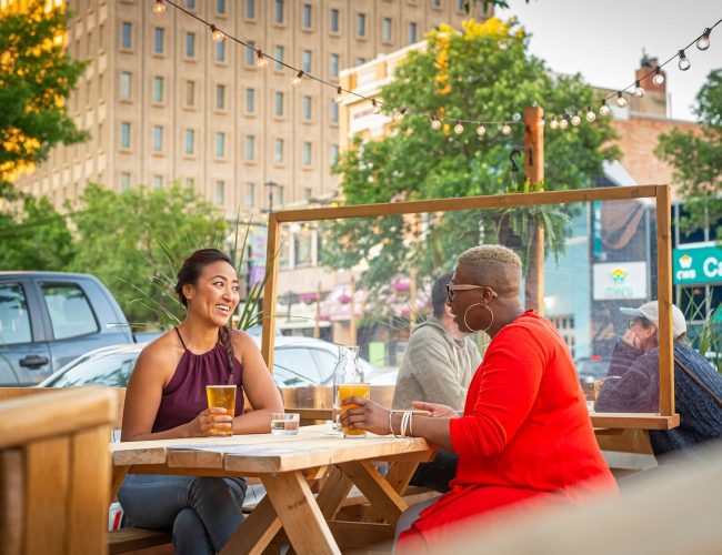 Two women sitting on a patio enjoying craft beer