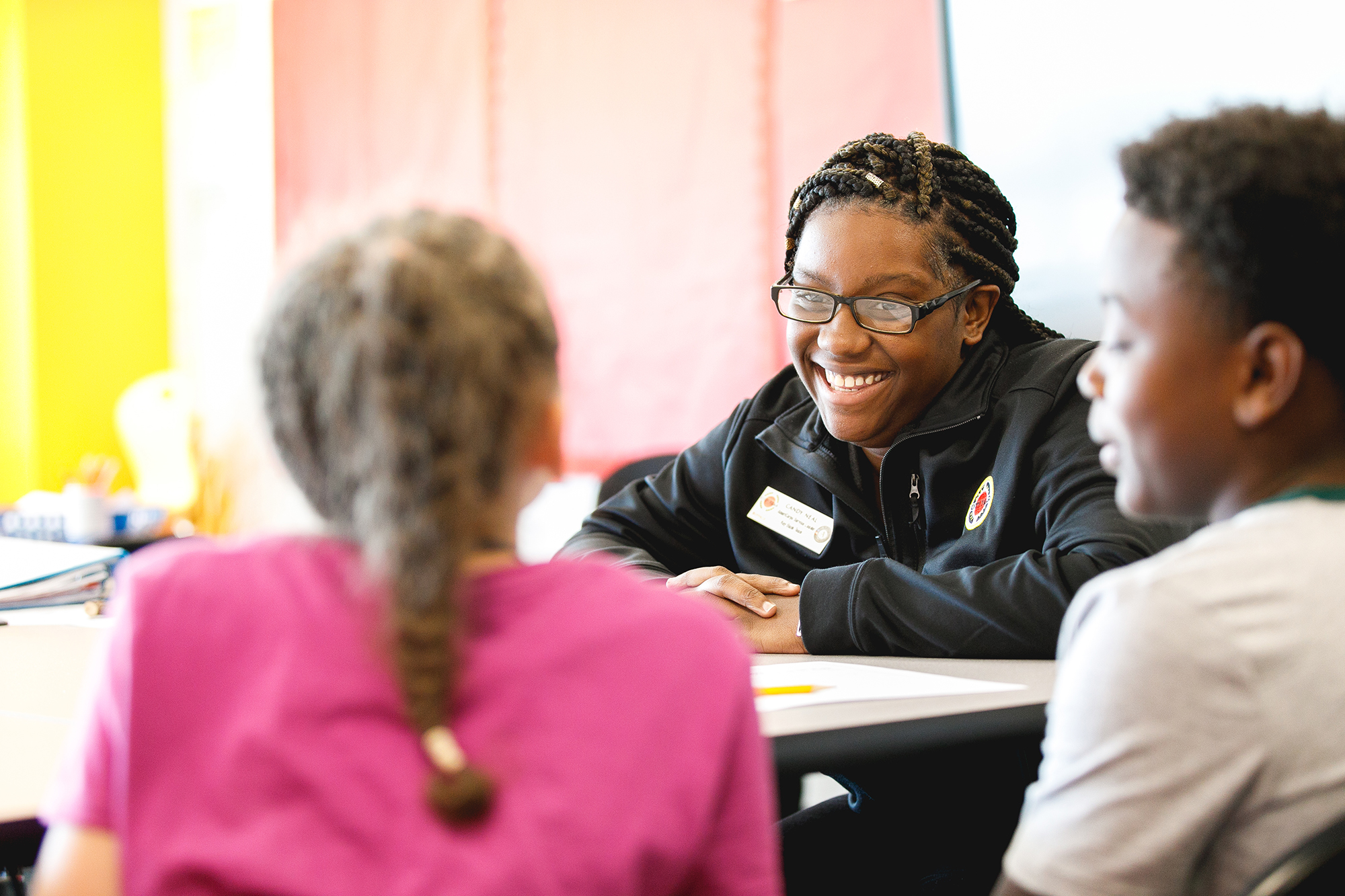 woman sitting at a table looking at two kids smiling