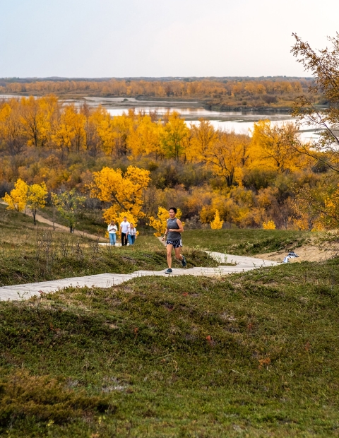 Man running in a park with lots of trees with autumn colours