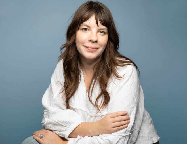 Headshot of Darby Sutherland against a blue background