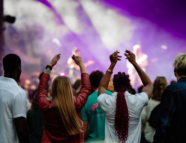 A crowd of people facing a stage illuminated by purple lights. A jazz band is playing on the stage.