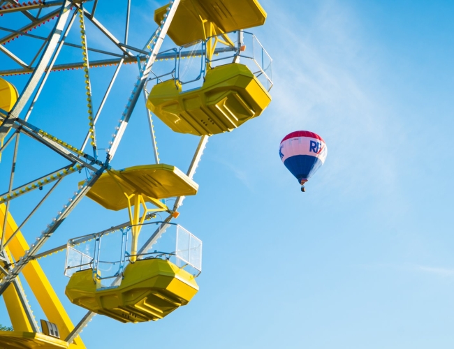 Ferris wheel with a hot air balloon floating in the sky