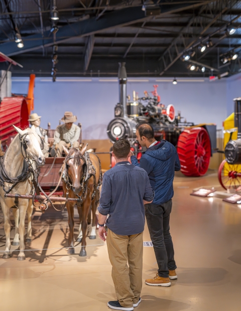 Two men standing in front of a horse carriage in the Western Development Museum