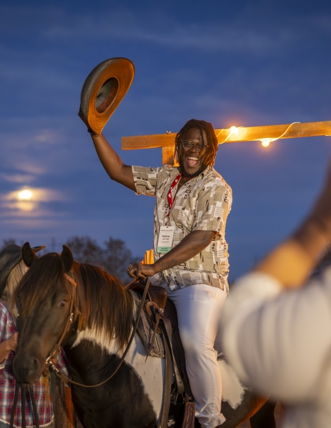 Man sitting on a horse holding a hat