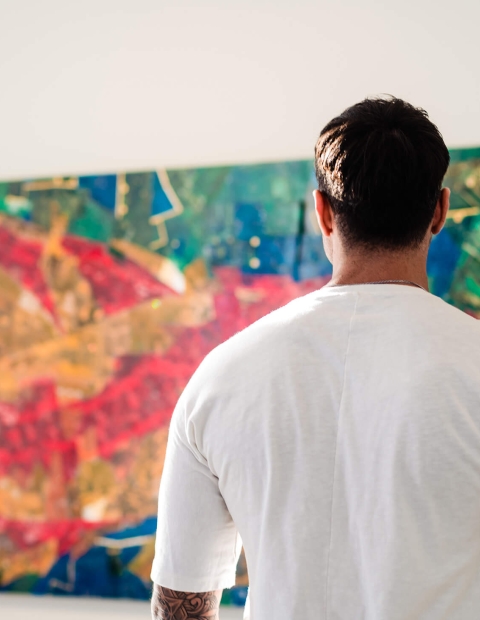 man with his arm around a woman looking at a large piece of artwork