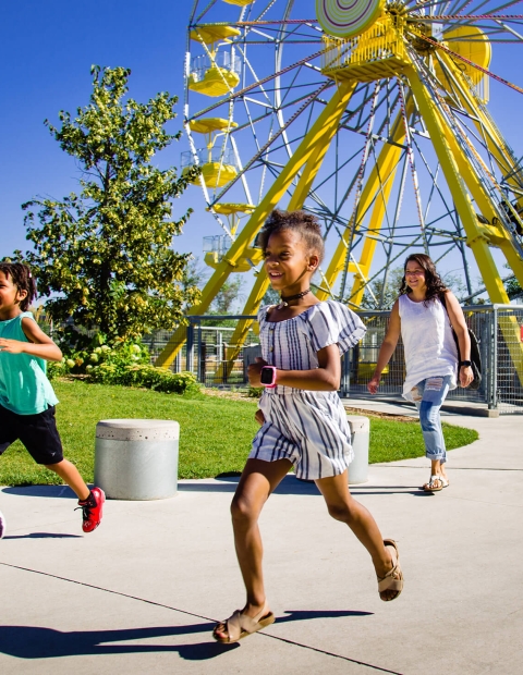 Children running and smiling at an amusement park