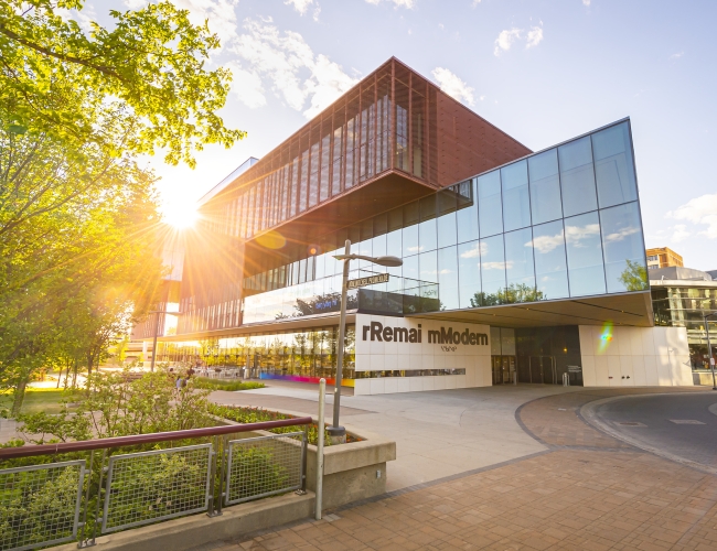 Exterior of the rRemi mModern building with the sun flaring off the windows